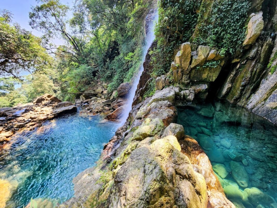 he stunning double pool of Pung Iyer Falls, featuring crystal-clear waters surrounded by lush greenery.