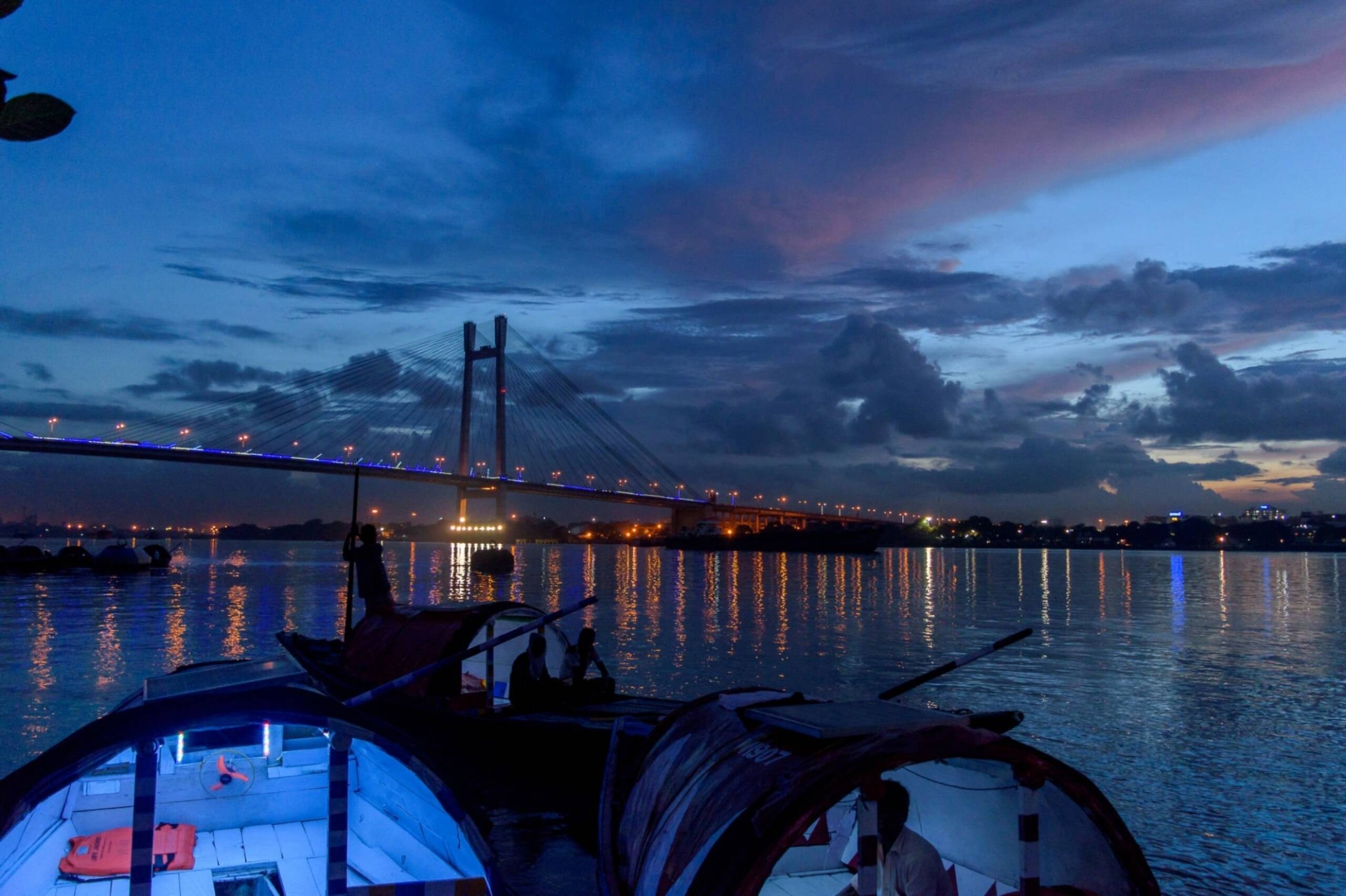 Silhouette of Vidyasagar Setu Bridge at Twilight, Framed by a Wooden Boat on the Hooghly River