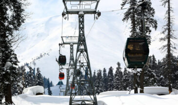 Skiers and tourists ride in a gondola lift, passing over the snow-covered slopes of the famous Gulmarg ski resort in Baramulla district, Jammu and Kashmir, India, on February 12, 2023. The gondola lift offers views of the Himalayan mountains and provides access to higher reaches for winter sports enthusiasts. (Photo by Nasir Kachroo/NurPhoto via Getty Images)
