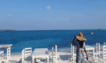6 Nights 7 Days Agatti-Kavaratti-Bangaram-Thinnakara Affordable Luxury Lakshadweep Package by SetMyTrip – White sandy beach with oceanfront dining setup and tourist enjoying the sea view.