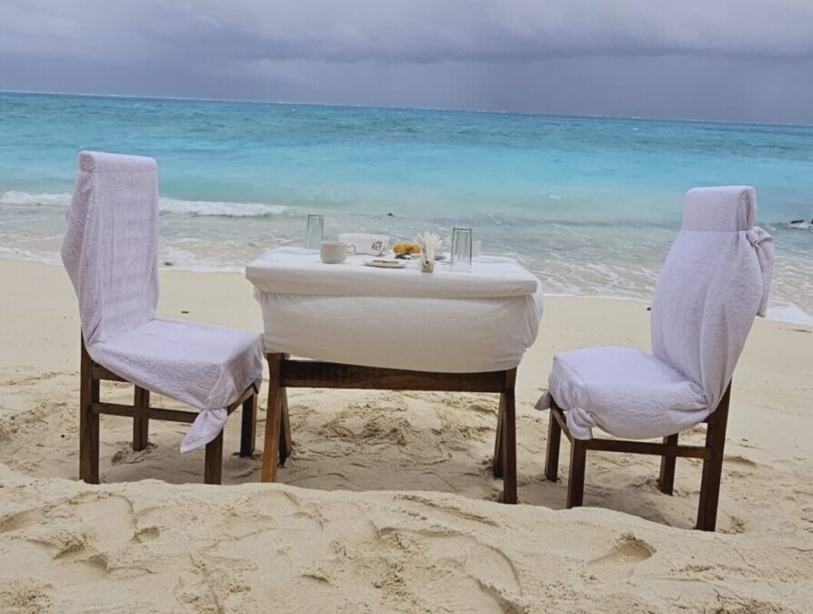 SetMyTrip 4 Nights Lakshadweep Agatti Beach Resort Stay Package (Honeymoon Special)– includes a private beach celebration set-up with an intimate dining table arranged on the white sands of Agatti Island, offering couples a romantic daytime experience by the turquoise sea.