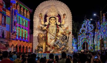 Jagaddhatri idol during the Chandannagar Puja immersion procession, surrounded by colourful festival lights and crowds at night.